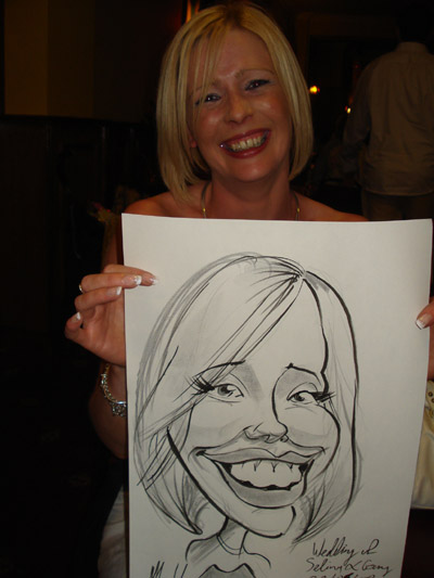 Blonde woman laughing holding a caricature of herself by Allan Cavanagh