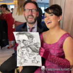 Seated couple laughing and holding a caricature by Allan Cavanagh