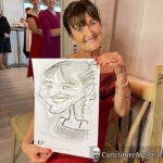 Seated woman laughing and holding caricature at a wedding in Spanish Point Hotel County Clare