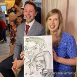 Young couple seated holding caricature and laughing