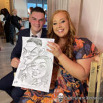 Young couple seated holding caricature and laughing